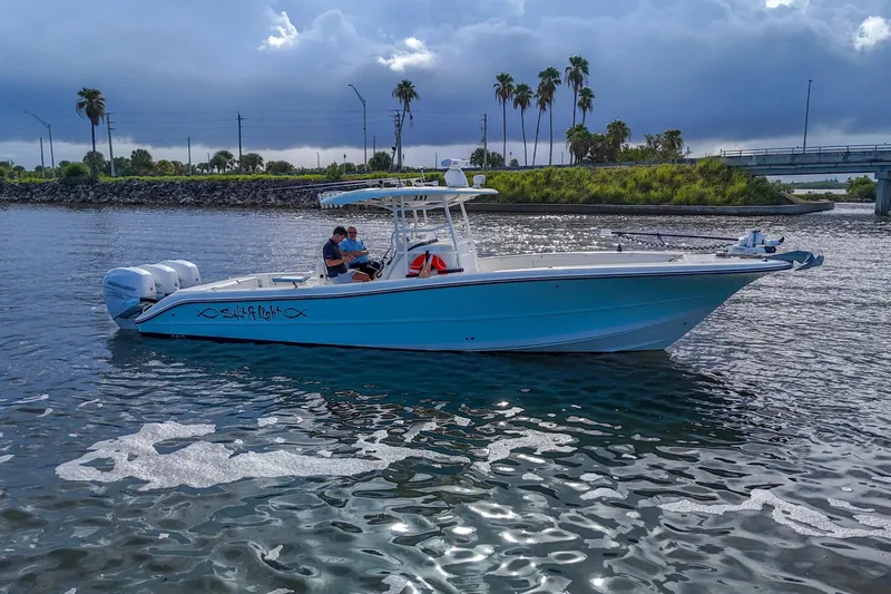  Yacht Photos Pics 2008 Triton 351 CC boat on water with two people, palm trees in background.