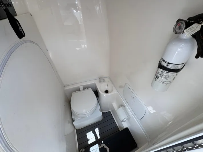  Yacht Photos Pics 2021 Fountain 38TE boat bathroom with toilet, fire extinguisher, and white interior.