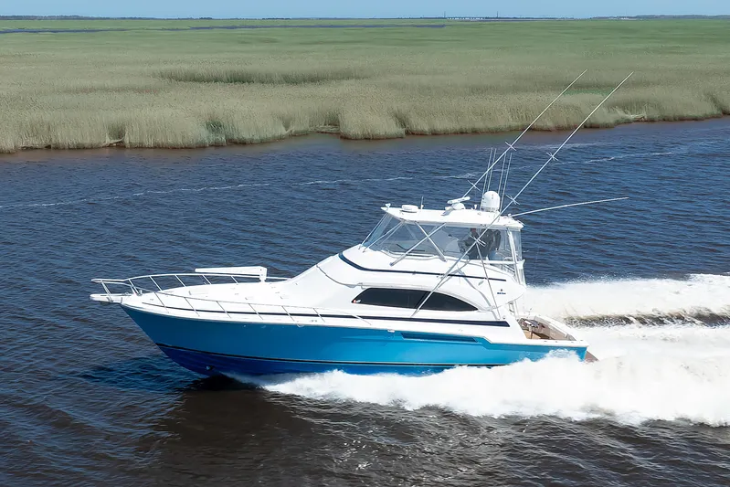 Dock Side Yacht Photos Pics 2007 Bertram 570 Convertible yacht cruising on a river with lush green banks.