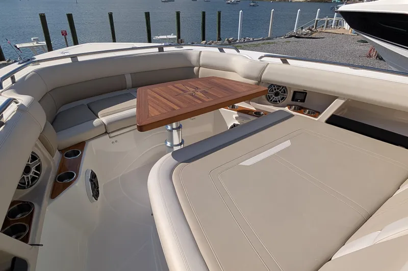  Yacht Photos Pics Luxurious seating area on 2024 Boston Whaler 350 Realm boat with wooden table and cup holders.