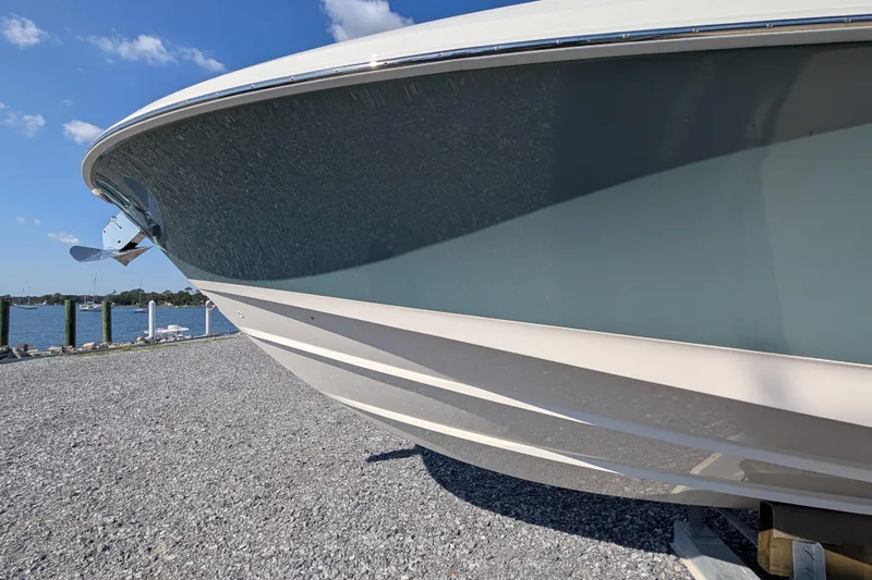  Yacht Photos Pics 2024 Boston Whaler 350 Realm boat on gravel near waterfront, under clear blue sky.