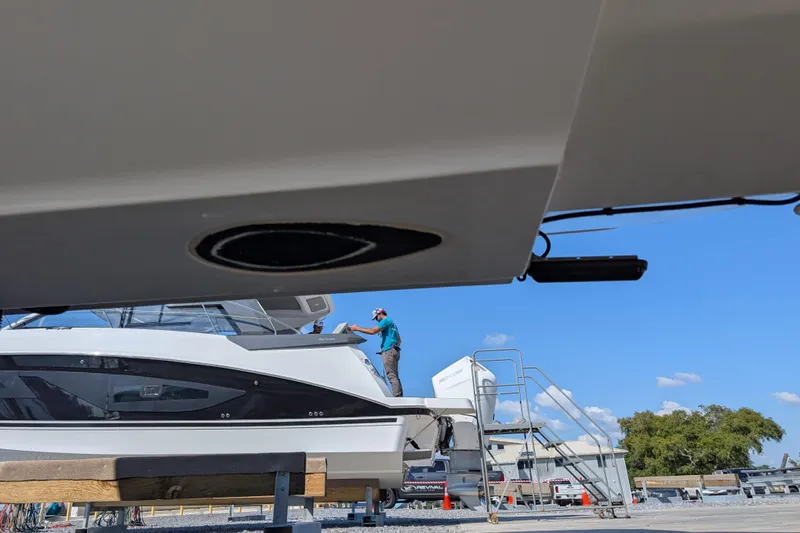  Yacht Photos Pics 2024 Boston Whaler 350 Realm yacht in a shipyard, with a person working on deck.