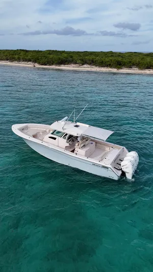  Yacht Photos Pics 2013 Grady-White Canyon 366 boat on clear turquoise water near a lush coastline.