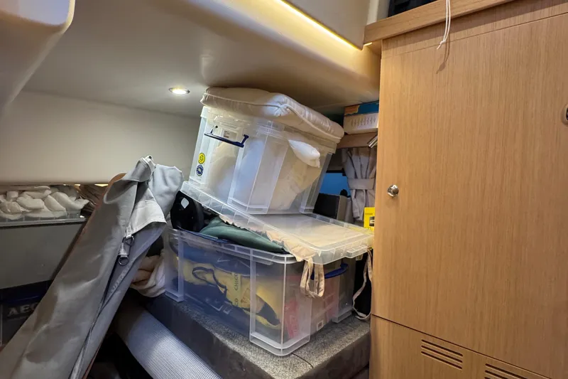 Annie Yacht Photos Pics Storage area inside 2023 Nimbus 405 Coup&eacute;, featuring organized plastic containers and wooden cabinetry.