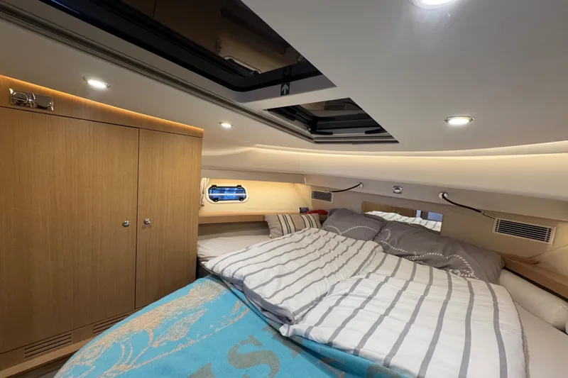 Annie Yacht Photos Pics Luxurious cabin interior of 2023 Nimbus 405 Coup&eacute; with cozy bedding and wooden cabinetry.
