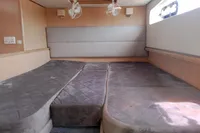 2023 Seawind 1600 Passagemaker cabin with plush gray bedding and wooden interior.