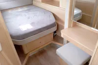 2023 Seawind 1600 Passagemaker cabin with bed, wooden interior, and small vanity area.
