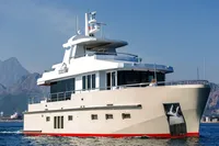 Luxury Bering 60 yacht cruising on water, 2012 model, with scenic mountain backdrop.