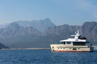 Luxury yacht Bering 60 (2012) cruising near scenic mountains and coastline.