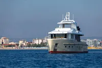 Bering 60 yacht from 2012 on calm sea with cityscape background.