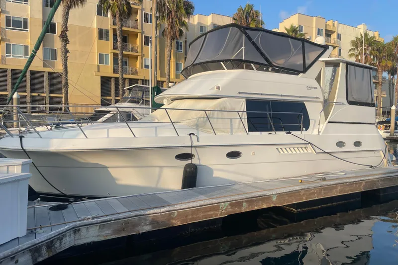  Yacht Photos Pics 1988 Marine Trader Aft Cabin yacht docked at marina with modern buildings in background.
