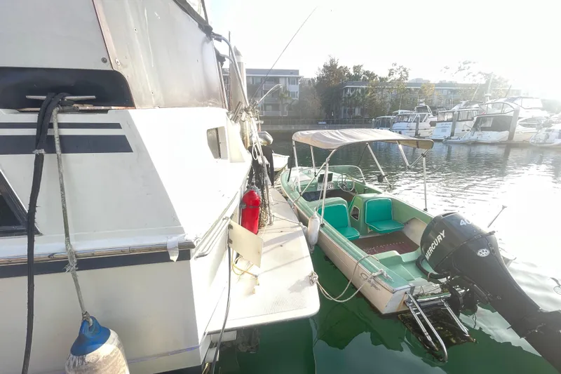  Yacht Photos Pics 1988 Marine Trader Aft Cabin yacht docked beside a small motorboat in a marina.