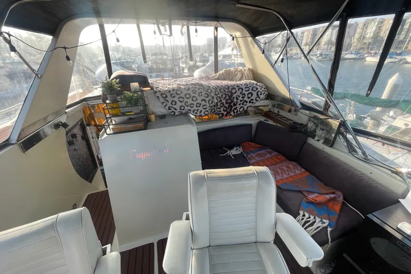  Yacht Photos Pics 1988 Marine Trader Aft Cabin interior with cozy seating, decor, and marina view.