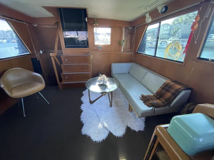  Yacht Photos Pics 1988 Marine Trader Aft Cabin interior with sofa, chair, and table, featuring large windows and cozy decor.