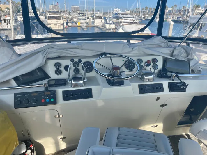  Yacht Photos Pics 1988 Marine Trader Aft Cabin helm with steering wheel, controls, and marina view.