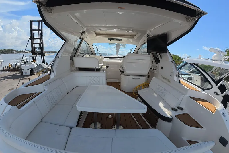  Yacht Photos Pics 2021 Sea Ray Sundancer 350 Coupe interior with seating, table, and helm, docked by the water.