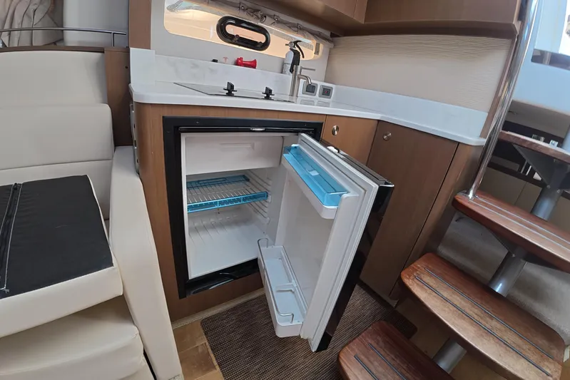  Yacht Photos Pics Interior of 2021 Sea Ray Sundancer 350 Coupe with open mini fridge and kitchenette.