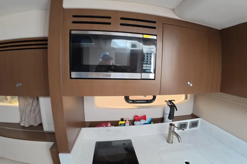  Yacht Photos Pics Modern kitchen area in 2021 Sea Ray Sundancer 350 Coupe yacht with microwave and sink.