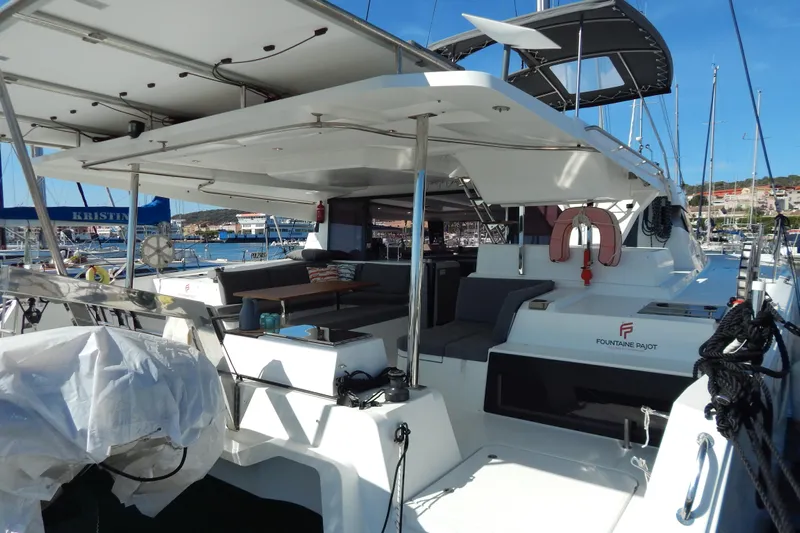  Yacht Photos Pics 2023 Fountaine Pajot Catamaran Elba 45 docked, featuring spacious outdoor seating and modern design.