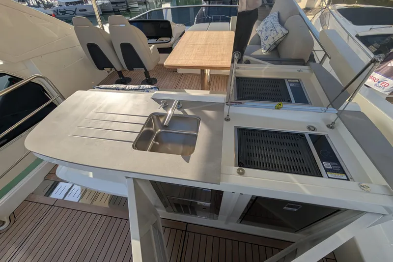  Yacht Photos Pics Luxurious 2025 Absolute 52 FLY yacht flybridge with sink, grill, and seating area.
