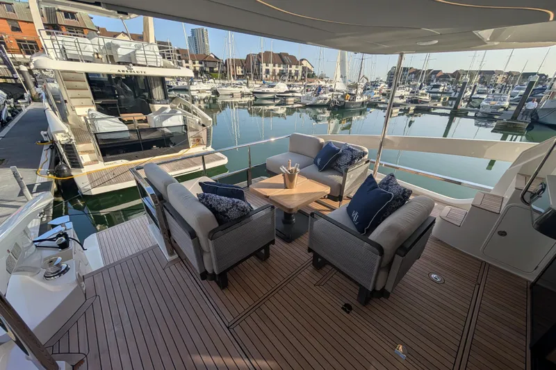  Yacht Photos Pics Luxurious 2025 Absolute 52 FLY yacht with elegant seating, docked in a serene marina.