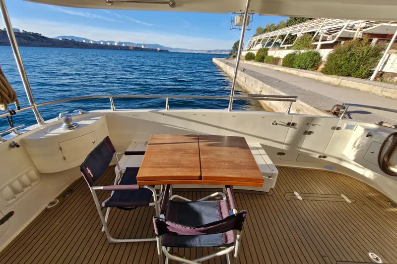 Mazu Yacht Photos Pics Deck of 2011 Adagio 58 yacht with table and chairs, overlooking serene waterfront.