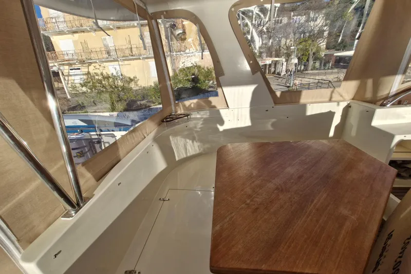 Mazu Yacht Photos Pics Interior view of 2011 Adagio 58 yacht with wooden table and large windows.