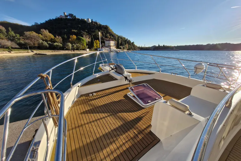 Mazu Yacht Photos Pics Luxury Adagio 58 yacht deck, 2011 model, cruising near scenic coastline under clear blue sky.