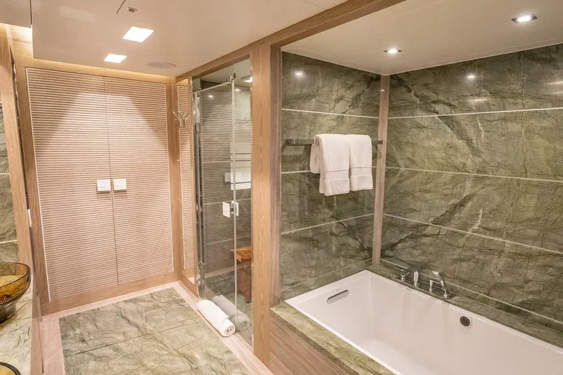 Short Story Yacht Photos Pics Luxurious bathroom with marble tiles, glass shower, and bathtub in Horizon RP120 yacht, 2017.