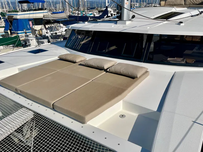 Bright Side Yacht Photos Pics 2019 Fountaine Pajot Saona 47 catamaran with sunbathing cushions on deck, docked at marina.