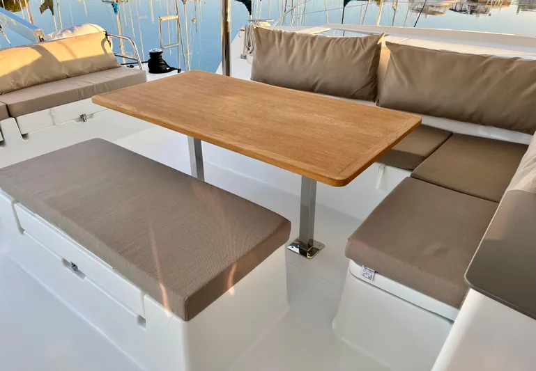 Bright Side Yacht Photos Pics Spacious seating area on 2019 Fountaine Pajot Saona 47 catamaran with cushioned benches and wooden table.