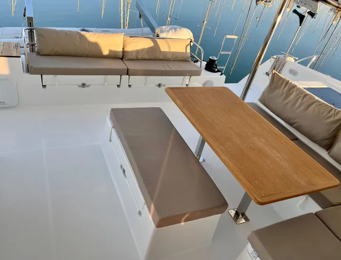 Bright Side Yacht Photos Pics 2019 Fountaine Pajot Saona 47 yacht deck with cushioned seating and wooden table.