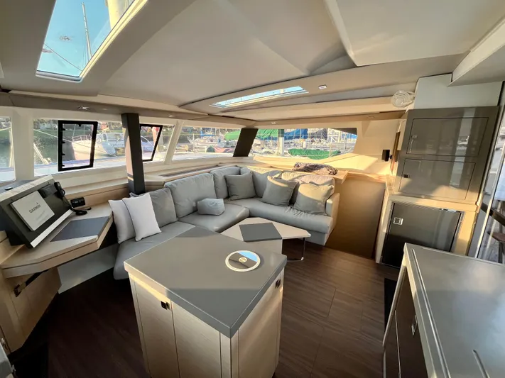 Bright Side Yacht Photos Pics Luxurious interior of 2019 Fountaine Pajot Saona 47 catamaran with modern furnishings and panoramic windows.
