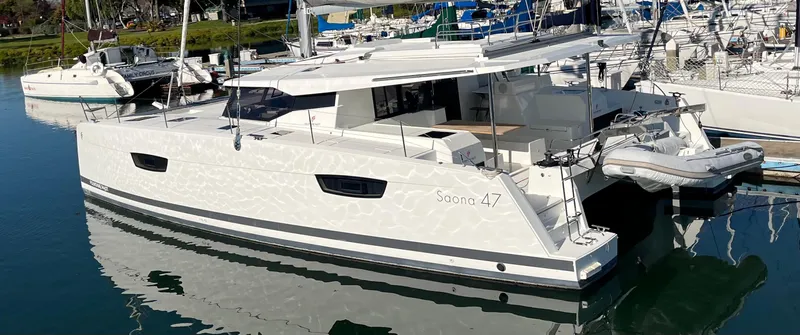 Bright Side Yacht Photos Pics 2019 Fountaine Pajot Saona 47 catamaran docked in a marina, reflecting on calm water.