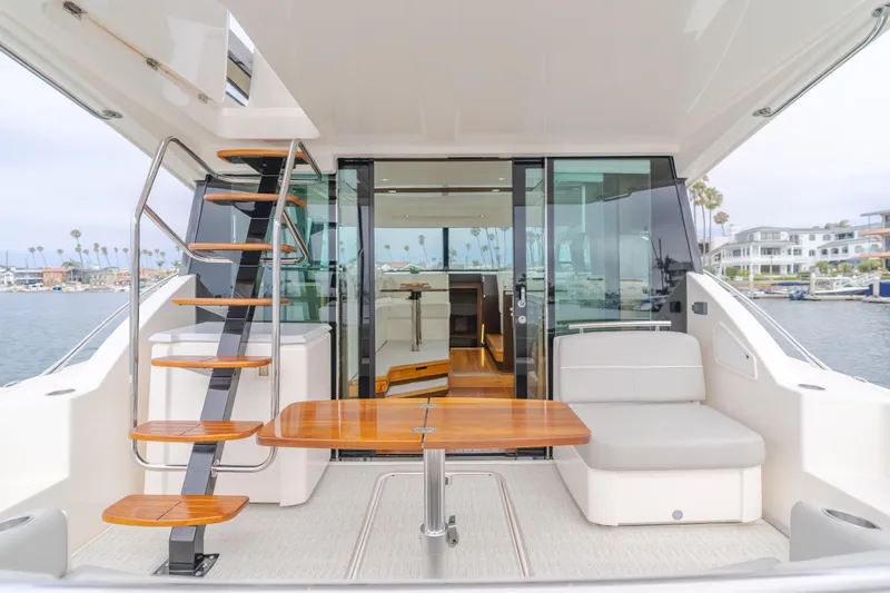 Chapter Three Yacht Photos Pics 2018 Tiara F44 yacht interior with modern seating, wooden table, and staircase, docked by waterfront homes.