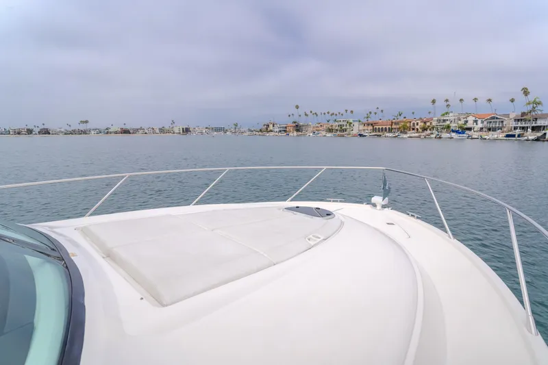 Chapter Three Yacht Photos Pics Bow view of 2018 Tiara F44 yacht cruising near coastal homes under cloudy skies.