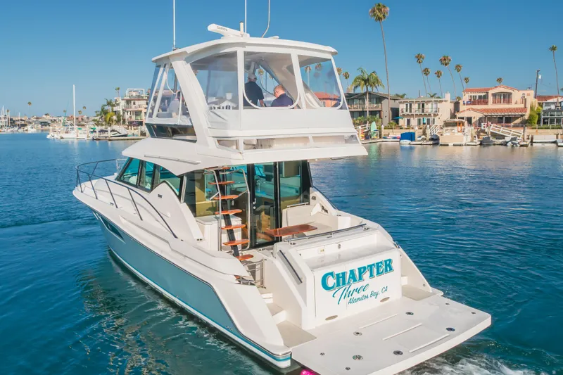 Chapter Three Yacht Photos Pics 2018 Tiara F44 yacht cruising in a sunny marina with palm trees and waterfront homes.