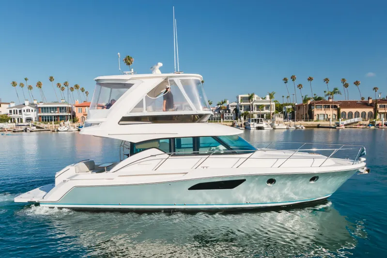 Chapter Three Yacht Photos Pics 2018 Tiara F44 yacht cruising in a scenic harbor with palm trees and waterfront homes.