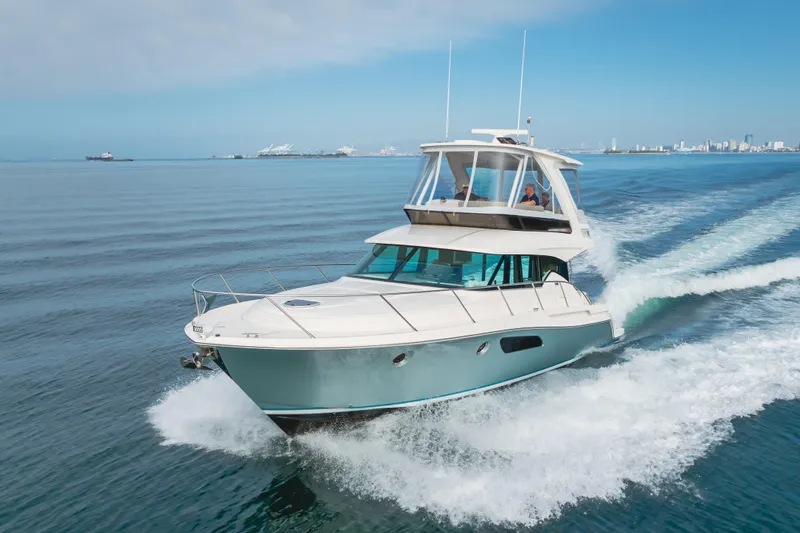 Chapter Three Yacht Photos Pics 2018 Tiara F44 yacht cruising on open water with city skyline in background.