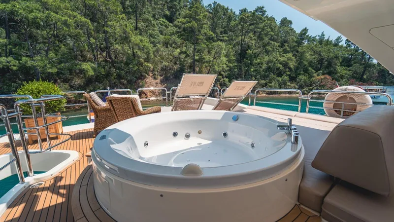  Yacht Photos Pics Luxurious 2013 Azimut 84 yacht deck with jacuzzi and sun loungers, surrounded by lush greenery.