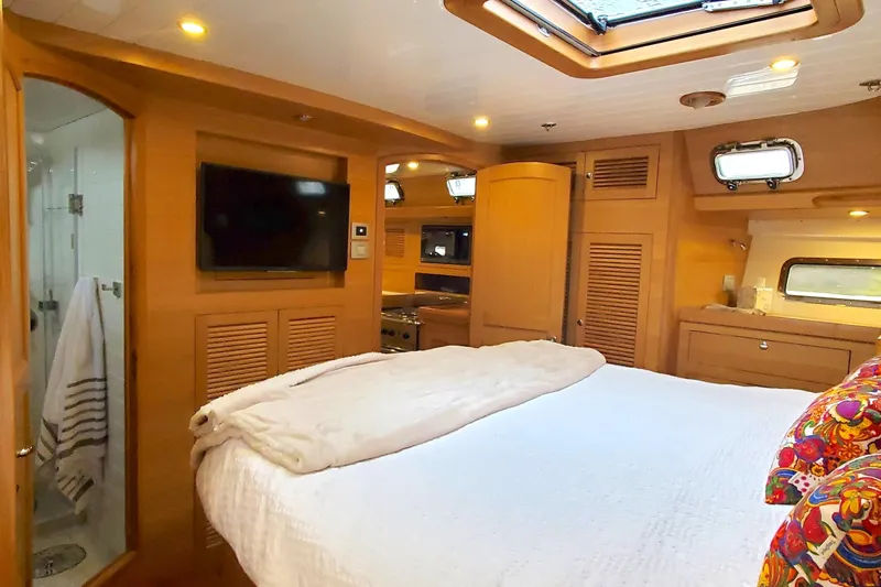 Centurion Yacht Photos Pics Luxurious 2023 Bluewater 56 yacht interior with cozy bedroom, TV, and elegant wood finishes.
