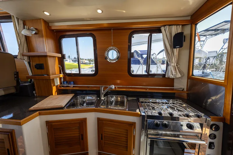  Yacht Photos Pics 2023 Ranger Tugs R-31 S interior kitchen with stove, sink, and wooden cabinetry.