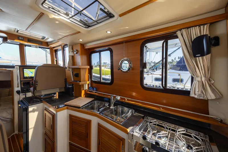  Yacht Photos Pics 2023 Ranger Tugs R-31 S interior with kitchen, wooden cabinetry, and windows.