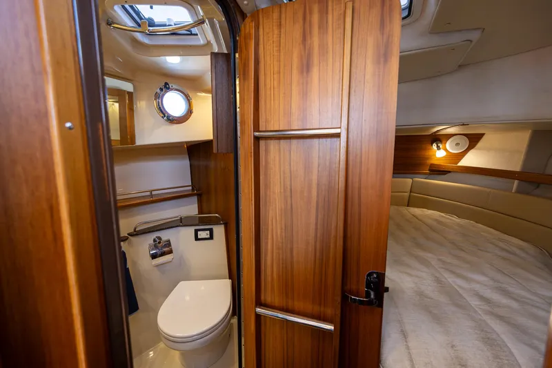  Yacht Photos Pics 2023 Ranger Tugs R-31 S interior with wooden door, compact bathroom, and cozy sleeping area.