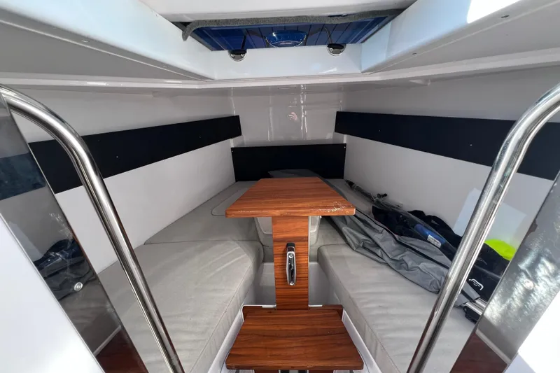  Yacht Photos Pics 2024 XO Boats EXPLR 10 S Plus cabin interior with wooden table and cushioned seating.