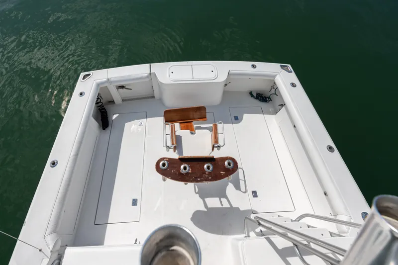  Yacht Photos Pics Cabo Convertible 2000 boat deck with fishing chair, surrounded by calm green water.
