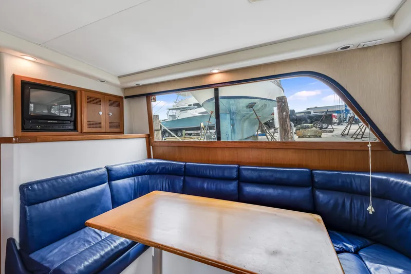  Yacht Photos Pics Interior of 2000 Cabo Convertible yacht with blue seating and wooden table.