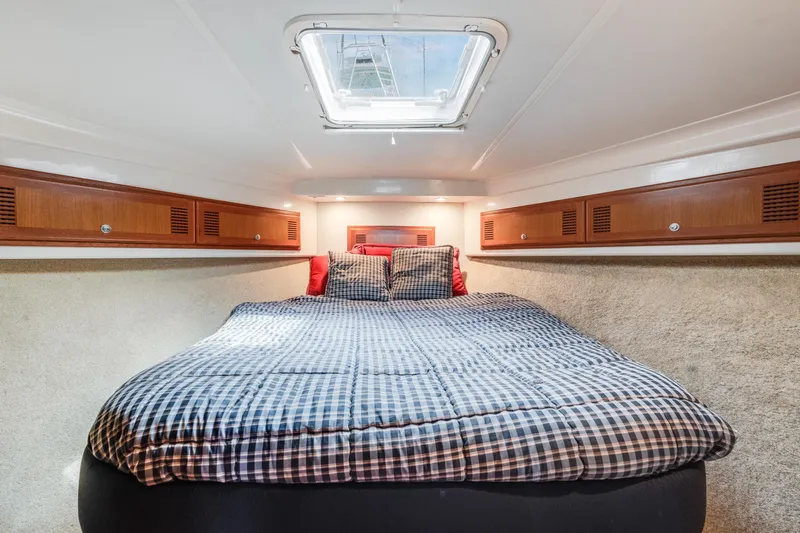  Yacht Photos Pics Cozy cabin interior of 2000 Cabo Convertible boat with skylight and checkered bedding.