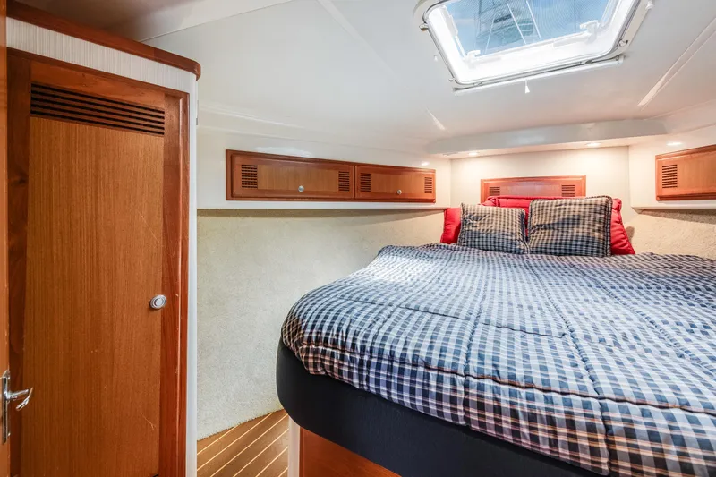  Yacht Photos Pics Cozy cabin interior of 2000 Cabo Convertible boat with bed and wooden accents.