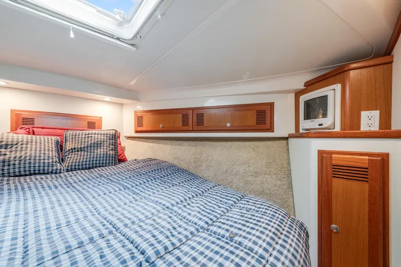  Yacht Photos Pics Cozy cabin interior of 2000 Cabo Convertible with plaid bedding and wooden storage cabinets.